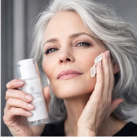 Femeie cu păr argintiu aplicând Fillift Massage Mask 3in1 Alissa Beauté pe obraji cu vârfurile degetelor, flacon 200ml vizibil. Mască-masaj cu Hema'Tite, Centella Reversa și Collalift®18, linia UPLIFT anti-îmbătrânire.