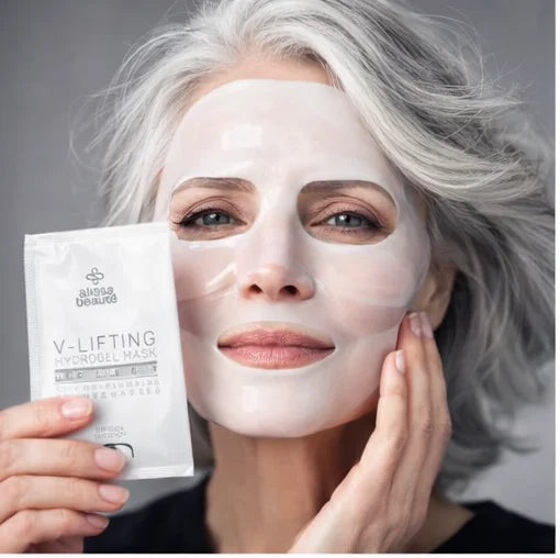Femeie cu păr argintiu aplicând masca hidrogel V-Lifting de la Alissa Beauté pe față, ținând pachetul produsului A249. Efect de lifting facial vizibil, linia UPLIFT anti-îmbătrânire.